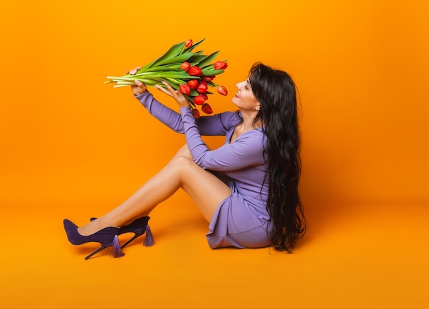 Beautiful woman with a bouquet of spring tulips on a yellow background March 8 womens day