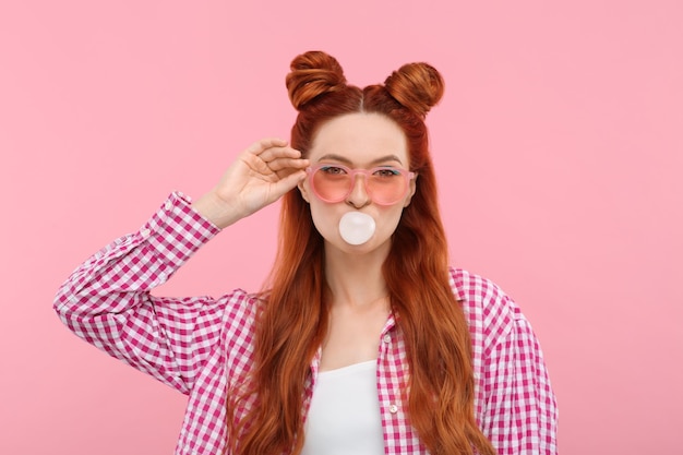 Photo beautiful woman with bright makeup blowing bubble gum on pink background