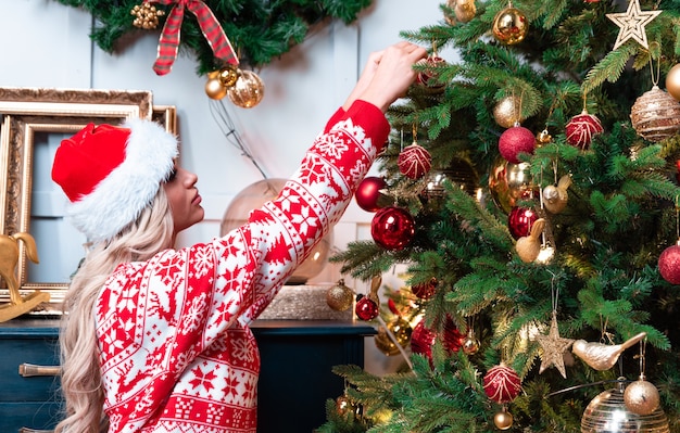 Bella donna con ghirlanda di abete rosso di natale con coni e palle di decorazione di capodanno con fiocchi di neve e luci.