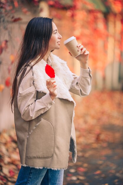 Красивая женщина с кофе в осеннем парке под осенней листвой в теплый день