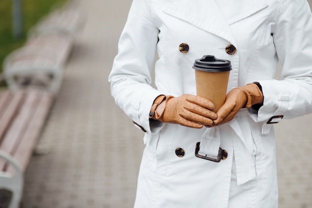 Beautiful woman with coffee cup near office building.