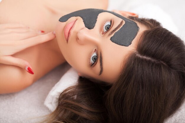 Beautiful Woman With Cosmetic Mask on Face Girl Gets Treatment in Spa Salon against white Background