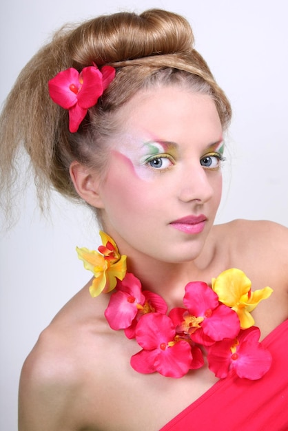 創造的なメイクの髪型と花を持つ美しい女性