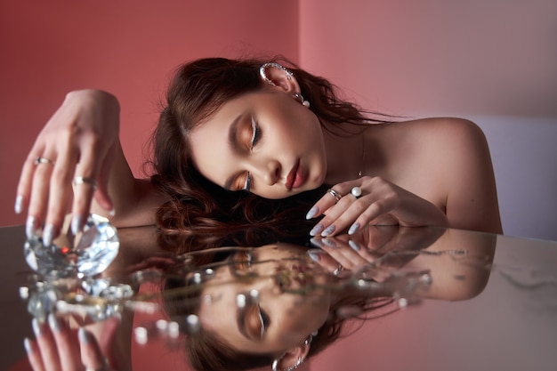 Beautiful woman with creative makeup is lying on the mirror