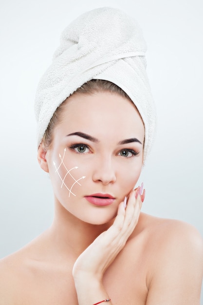 Photo beautiful woman with dark eyebrows and naked shoulders, wearing white towel on head holding hand with pink manicure