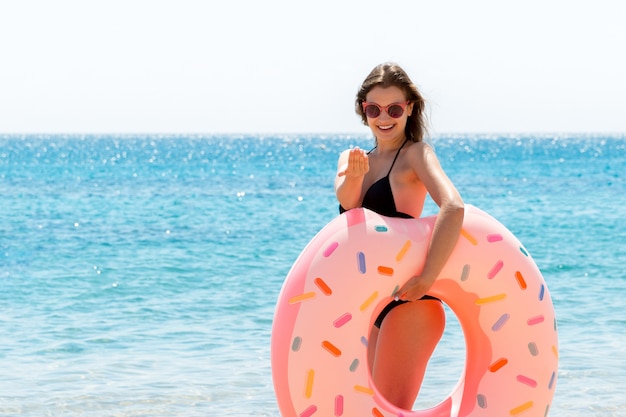 Beautiful woman with a donut rubber ring at the beach