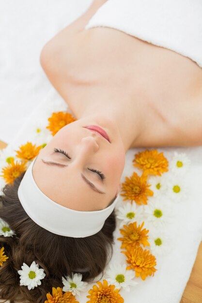 Beautiful woman with eyes closed and flowers in beauty salon