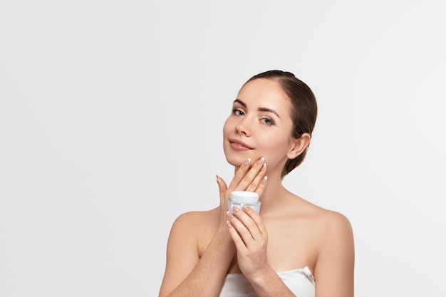 Bella donna con crema viso protezione della pelle skincare spa una giovane donna tiene crema idratante