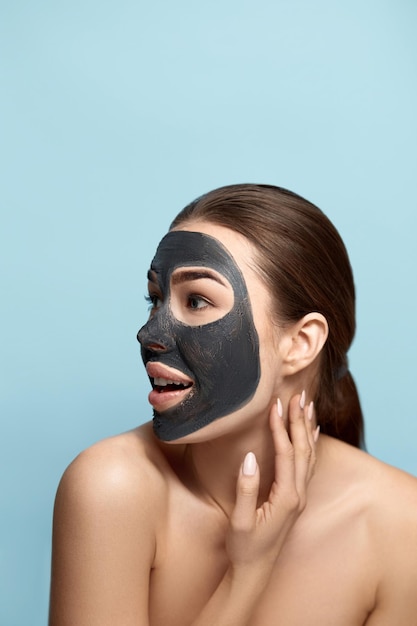 Beautiful woman with facial black mask touches her face beauty
skin care concept