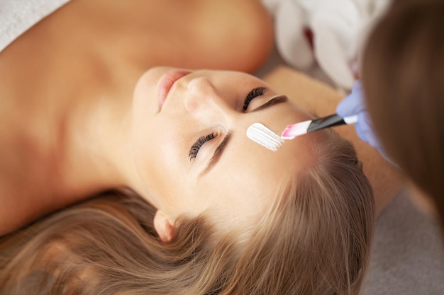 Beautiful woman with facial mask at beauty salon