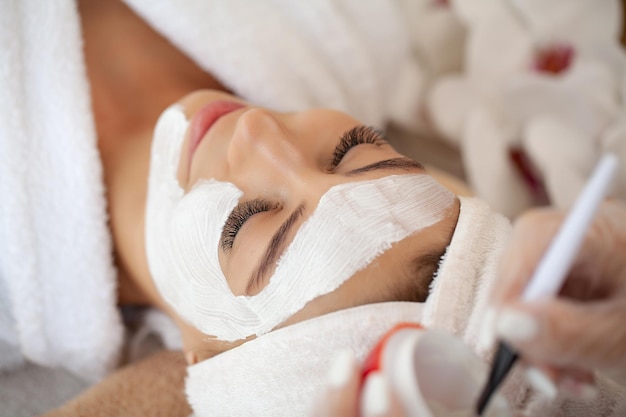 Foto bella donna con maschera facciale al salone di bellezza