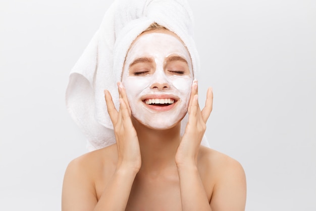 Beautiful woman with facial mask on white background