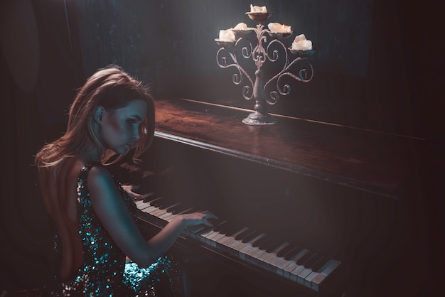 Фото Красивая женщина с причудливым элегантным платьем позирует в пианино
