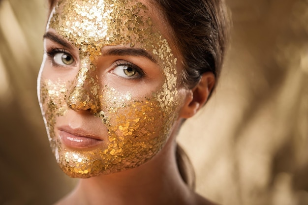 Photo beautiful woman with golden shining mask on her face for skin treatment