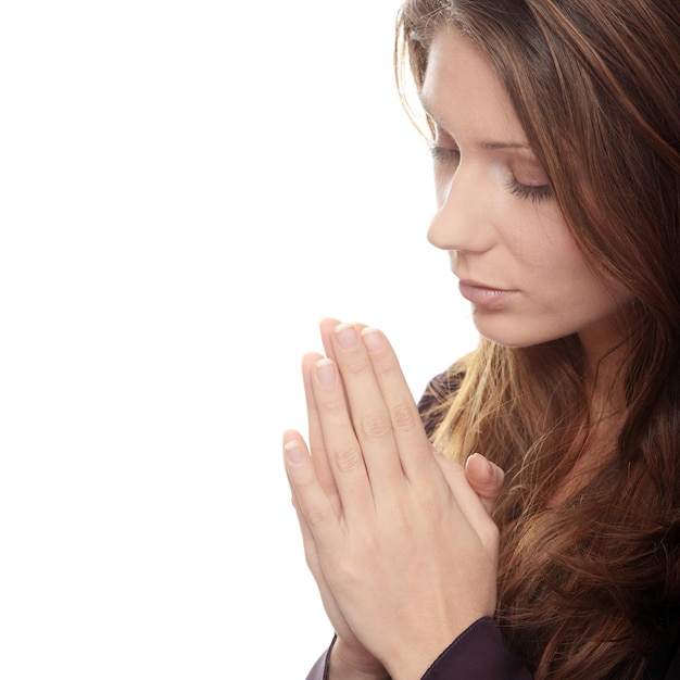 Beautiful woman with hands clasped praying against white background
