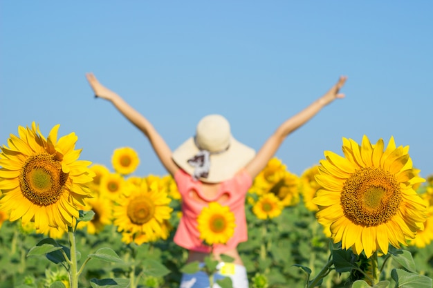 Beautiful woman with hat on her head in sunflowers field