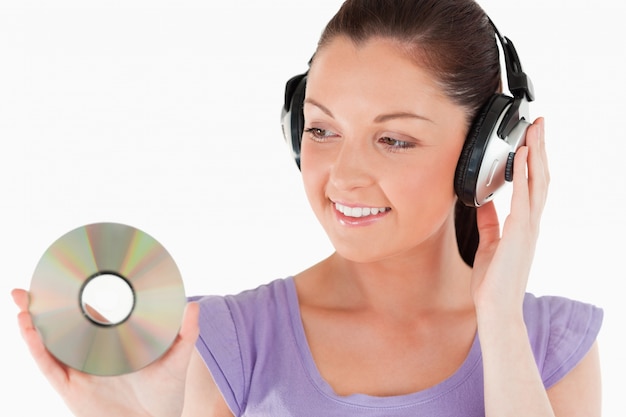 Beautiful woman with headphones holding a CD while standing