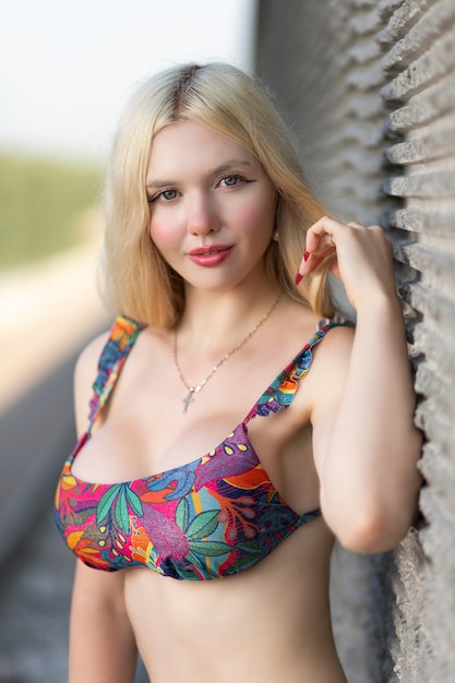 beautiful woman with healthy body wearing in a colotful swimsuit   under wall