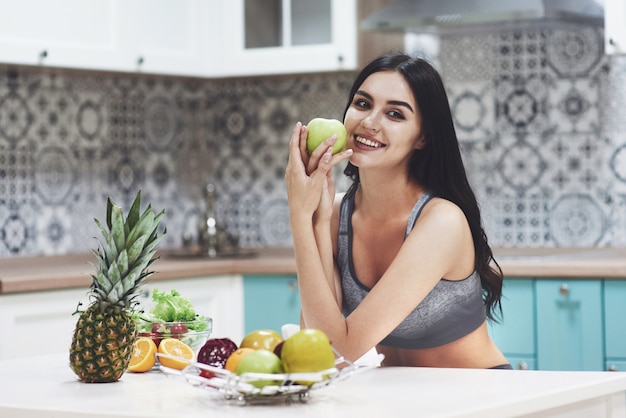 台所で健康食品の果物を持つ美しい女性