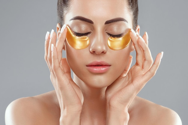 Beautiful woman with healthy perfect skin holds patchs beauty
face with gold cosmetics patch