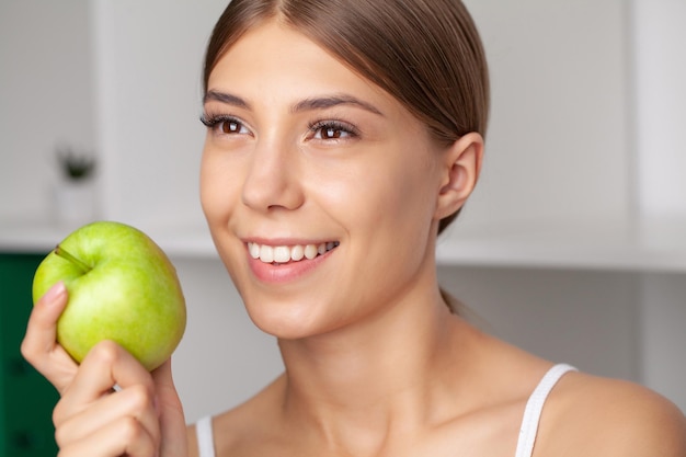 Beautiful woman with healthy white teeth holding green apple