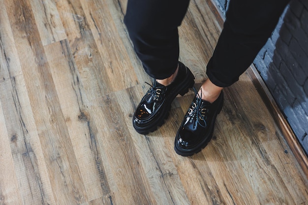 Красивая женщина с ногами в модной одежде стильные кожаные черные лакированные туфли на шнуровке крупным планом Женский образ в весеннем стиле