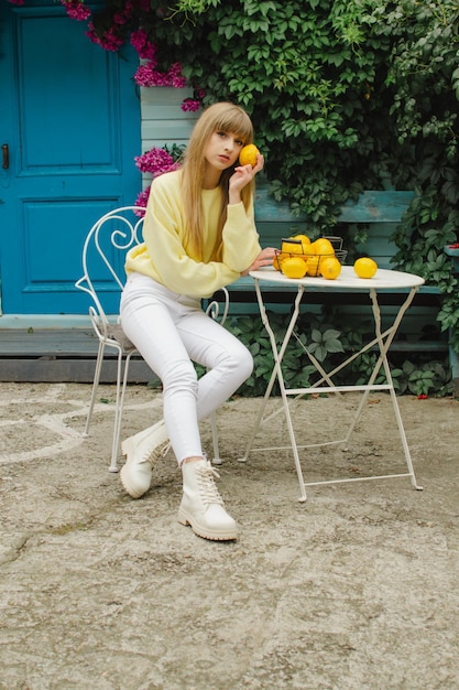 Beautiful woman with lemons sitting at the table