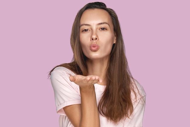 Photo beautiful woman with long dark hair blows kiss demonstrates good feelings says goodbye on distance