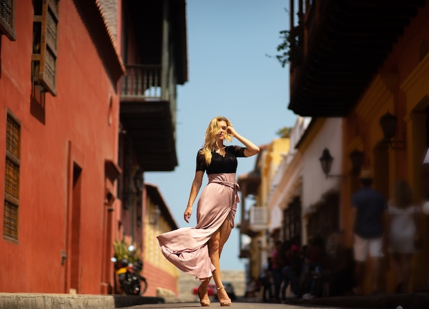 Beautiful woman with long dress walking alone at the colorful streets of the colonial walled city of Cartagena. Colombia.