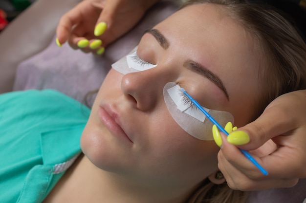 Beautiful Woman with long eyelashes in a beauty salon. Eyelash extension procedure. Lashes close up.