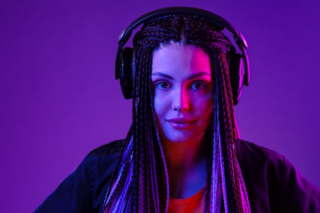 Beautiful woman with long hair in braids listening to music with headphones