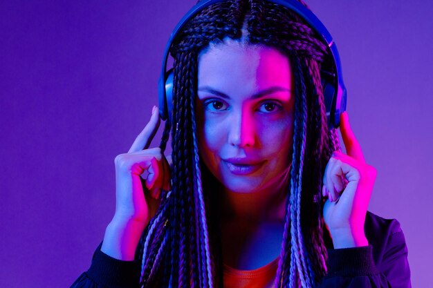Beautiful woman with long hair in braids listening to music with headphones