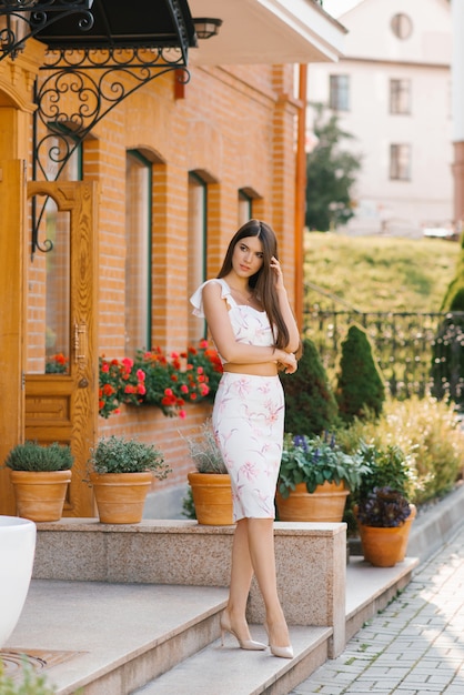 Beautiful woman with long hair and long legs is standing outside a house