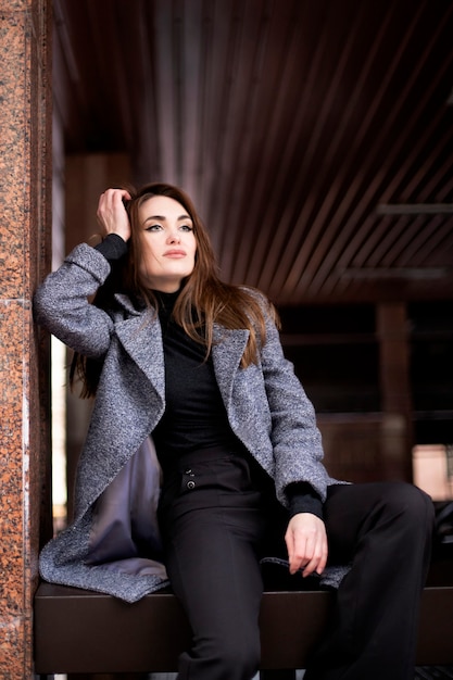 Beautiful woman with long hair
sits and looks into the distance. Woman of model appearance is sitting, dressed in warm clothes
