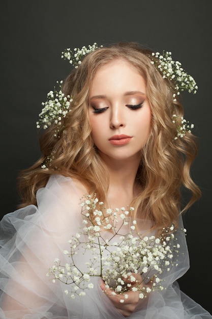 Beautiful woman with long healthy blonde curly hair make up and flowers