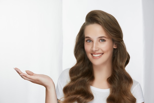 Beautiful woman with long healthy curly hair holding arm for copy space