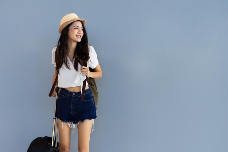 Photo 壁に立つ間荷物を持った美しい女性が目をそらしています