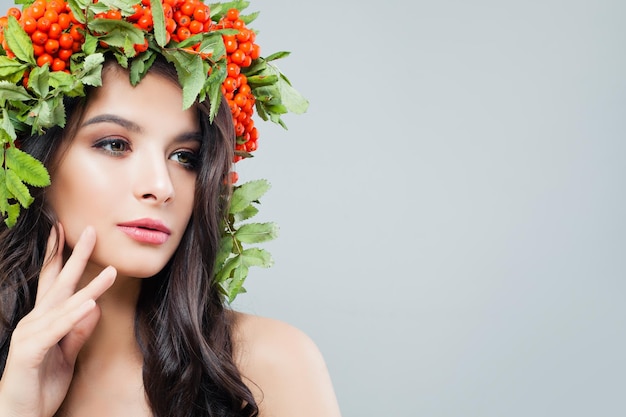 Beautiful woman with natural makeup perfect skin healthy hair and green leaves on background with copy space