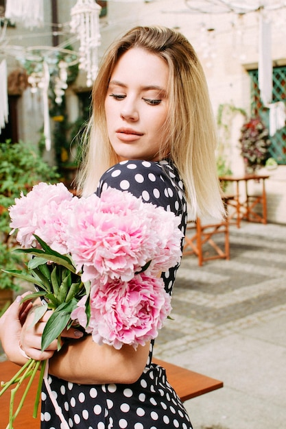 Beautiful woman with peonies on the street