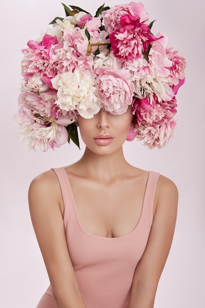 Foto bella donna con fiori di peonia rosa