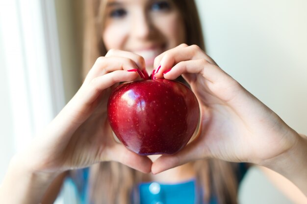 Beautiful woman with red apple at home.