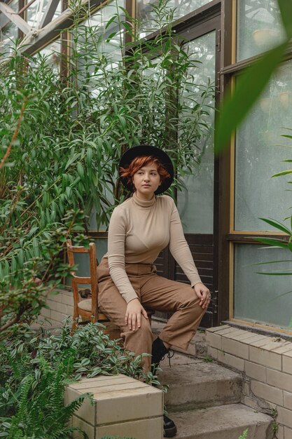 A beautiful woman with red hair among green branches of tropical plants