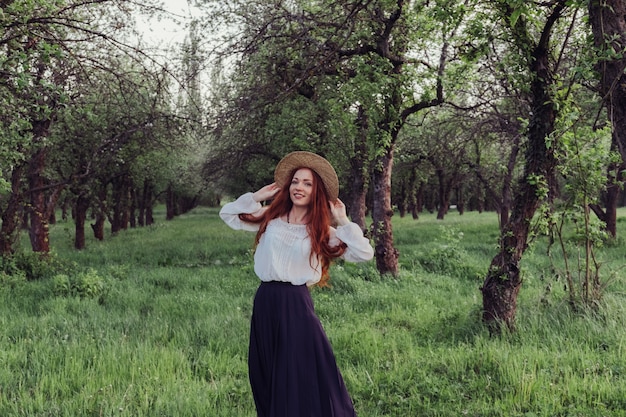 Foto bella donna con i capelli rossi in un cappello di paglia