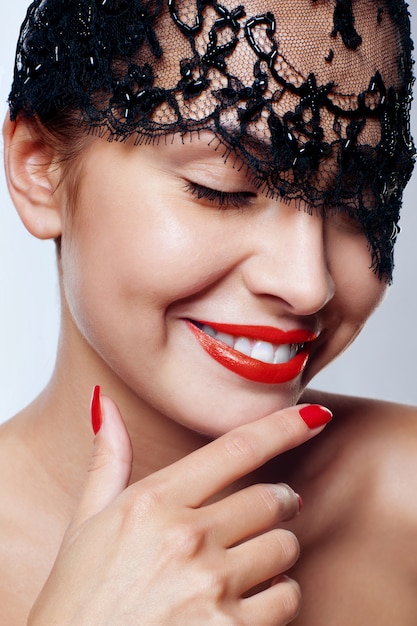 Beautiful woman with red lips and lace mask over her eyes. 