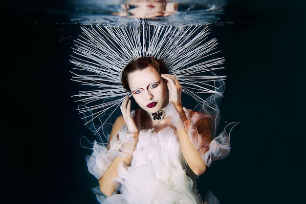 Beautiful woman with red lips and in women's jewellery underwater as the Virgin Mary