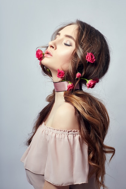 Bella donna con fiori di rosa tra i capelli lunghi