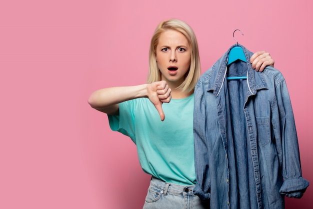 Foto bella donna con camicia su un gancio sul muro rosa