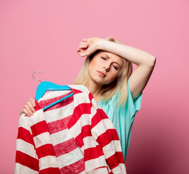 Beautiful woman with shirt on a hanger on pink wall