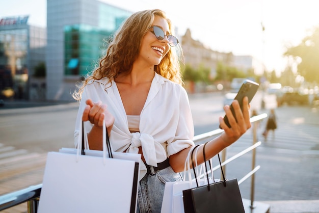 Beautiful woman with shopping bags makes selfie Woman walking after shopping Black friday