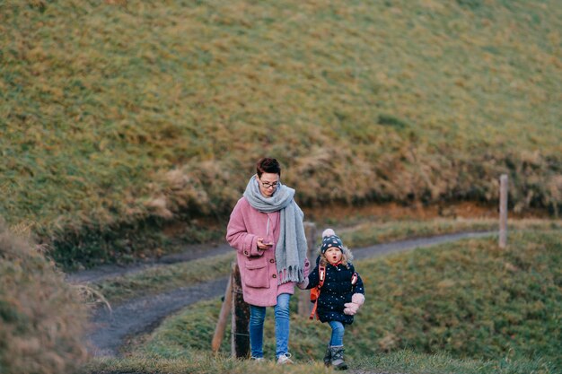 Beautiful woman with short haircut goes for a walk with her pretty daughter